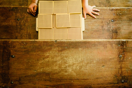 Hands of boy manipulating counting cubes on wooden background in montessori classroomの写真素材