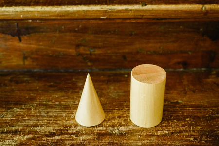 Solid wood shapes to study geometry and volumes, cones, triangles, squares, spheres on a warm wood background.の写真素材