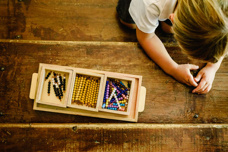 Hands of a child manipulating educational materials to learn to count in a Montessori classroom.の写真素材