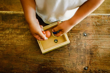 Child playing with small toy planets on an old wooden table.