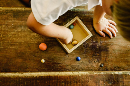 Child playing with small toy planets on an old wooden table.