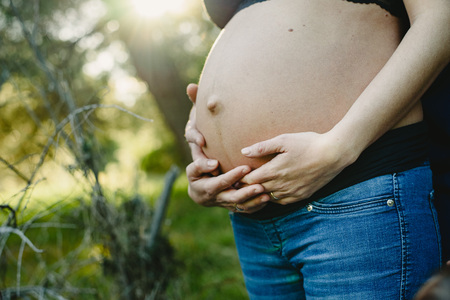 Belly of pregnant woman walking by in natureの写真素材