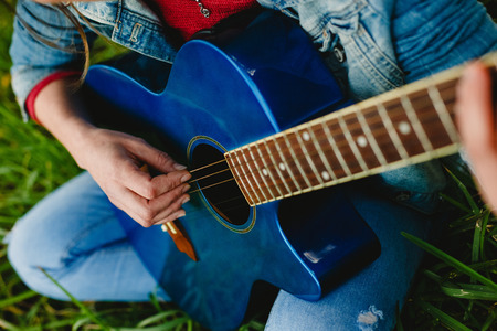 Young woman with blue guitar in the countryの写真素材