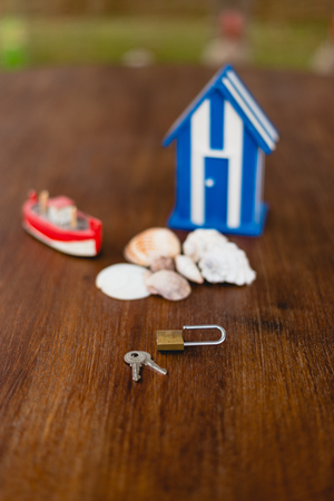 Padlock and keys of a beach house next to wooden toy house with maritime motives.の写真素材