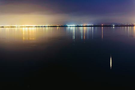 Pier on a lake at sunset with calm water and reflections of relaxing lights.の写真素材