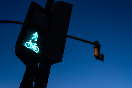 Traffic light in green for pedestrians and cyclists, with the figure of a cyclist. Night background for the concept of freeway and permission to continue.の写真素材