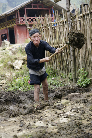 Sapa, Vietnam - May 11, 2013: Vietnamese farmer in a village of the Sapa Mountains, withdrawing mud...