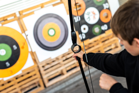 Boy aiming with a training bow at a bullseye at a fair.
