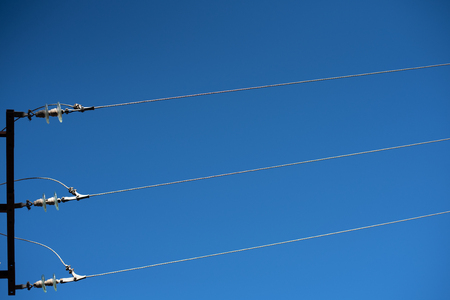 Electric cables seen from below with blue sky background.の写真素材