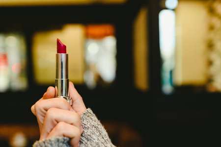 Red lipstick held by a woman's hand.の写真素材