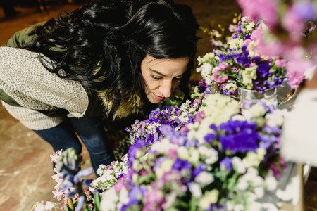 Brunette woman smelling flowers in a market at night.の写真素材