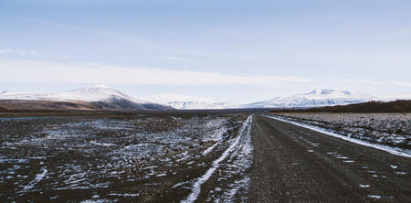 Gravel road in the snowy mountains of Iceland after a rainy day with mud