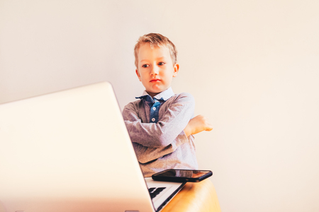Child 5 years working on a laptop with an angry face when business failing, humor image.の写真素材