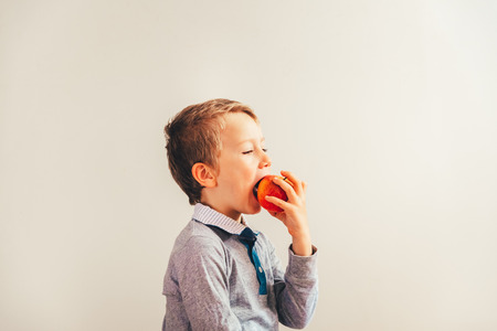 Child ready to eat an apple at a bite, isolated on white background with copy space.