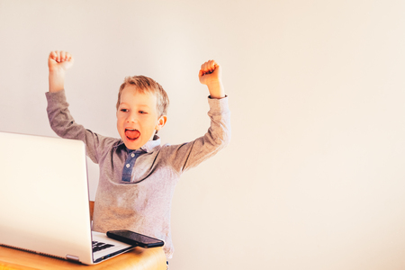 Child using a laptop and laughing at his success in business.の写真素材