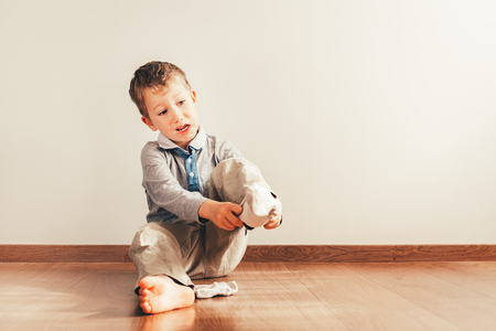 Child with lots of independence sitting on the floor putting on his socks with an expression of effortの写真素材