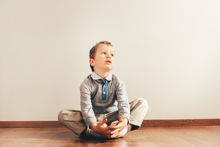 Child with lots of independence sitting on the floor putting on his socks with an expression of effortの写真素材