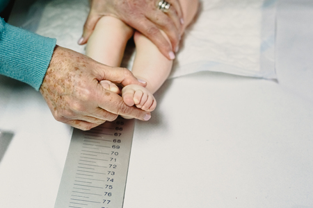 newly born in the clinic of the pediatrician measuring a height and height of the baby with the help of a ruler.の写真素材