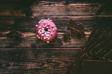 Aged wooden table with delicious pink donuts for lunch tasty sweets for young people, copy space.の写真素材