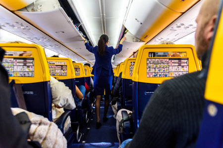 Valencia, Spain - March 8, 2019: Stewardess inside a Ryanair plane securing the top luggage before takeoff, walking down the aisle from behind.のeditorial素材