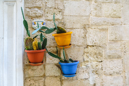 Three flower pots with flowers hanging from the stone facade of an Italian house.のeditorial素材