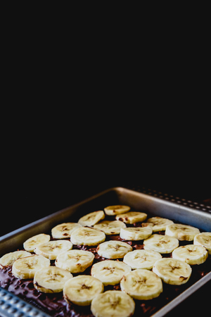 Sliced banana on a cake on a tray before baking it.の写真素材