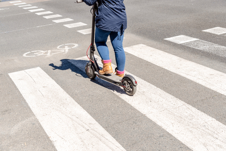 Detail of an electric scooter driven by a woman while waiting her turn to cross a road.の写真素材