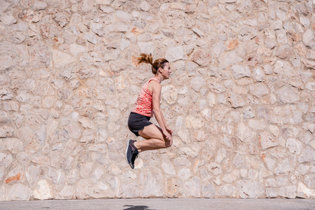 Middle aged woman athlete with fitness clothes doing exercises and running in the sun and sweating in summer.の写真素材