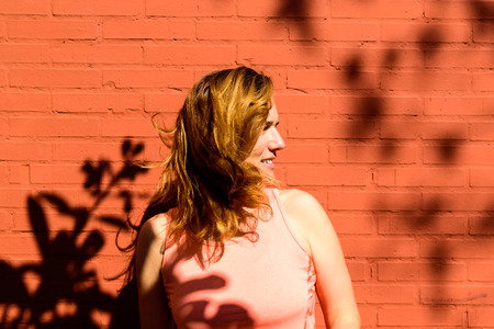 Middle aged woman athlete with fitness clothes happy to start life changing after her divorce, on red brick background at noon.の写真素材
