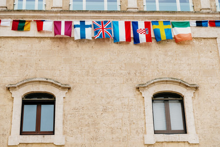 Flags of European countries hanging from a balcony in the Italian city of Matera.のeditorial素材