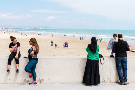Valencia, Spain - April 29, 2019: Young black women together with Muslim couple with woman with veil enjoying the holidays near the beach.のeditorial素材