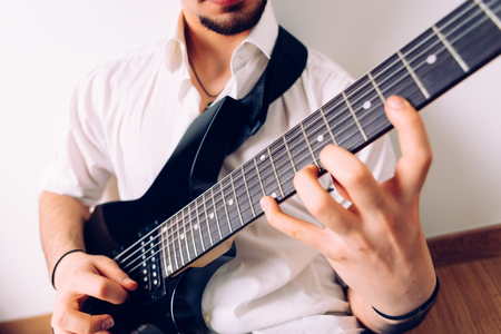 Close-up of the hands of a guitarist performing a song while pressing the strings.