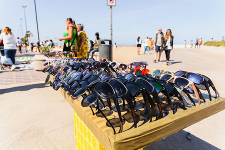 Valencia, Spain - May 12, 2019: Illegal immigrants selling false glasses and souvenirs to tourists...