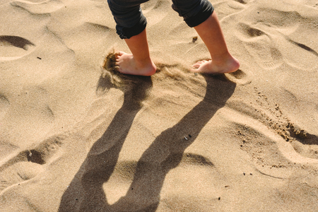 Feet of boy walking on the sand of the beach.の写真素材