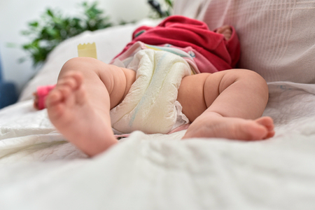 Newborn baby laying on a sofa with disposable diapers ready to change.の写真素材