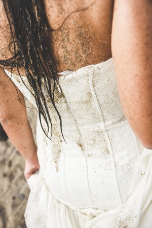 Back of a bride with her wedding dress smeared with sand from the beach.