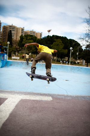 Valencia, Spain - March 24, 2012: Young latino doing stunts with his skate in a skate park.