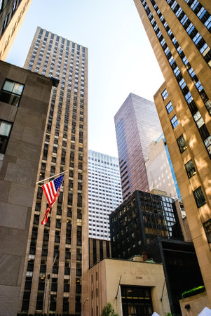 New york, usa- August 13, 2008: Vertical image of condensed and cramped American skyscrapers, with American flag attached to a facade.のeditorial素材