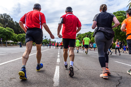 Valencia, Spain - May 19, 2019: Mature man blind runner and his companion joined by a cord to guide him during an amateur competition surrounded by other runners reaching the finish line.のeditorial素材
