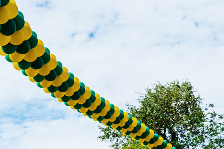 Background with copy space of many inflated balloons hanging isolated on a blue sky with clouds.の写真素材