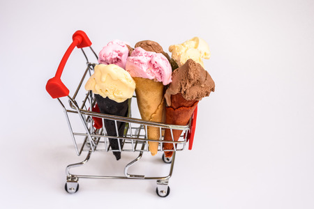 Shopping cart filled with vanilla and chocolate strawberry ice cream cones, buying tasty foods for...