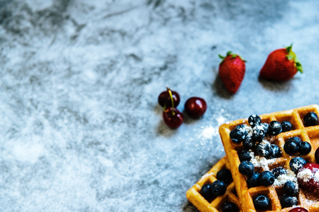 Close-up of a waffle with blueberries and strawberries with delicious aspect, isolated on abstract background with copy space for text.の写真素材