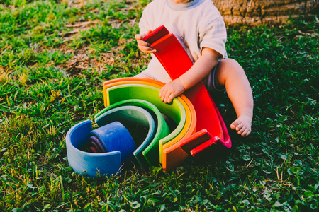 6 month old baby using to play a wooden rainbow puzzle, improving his skills, view from above.の写真素材