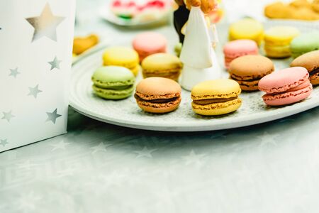 Dessert at a wedding, with figures of newly-married dolls, on a plate with macarons.の写真素材