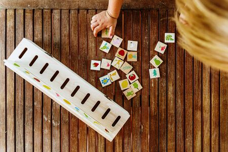 Child having fun with an educational wooden game at school, to make pairs, useful to improve the memory and dexterity of their hands.の写真素材