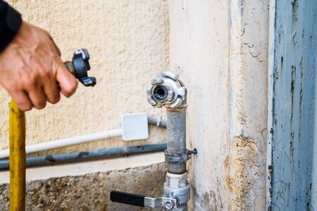 Operator connecting a hose to a tap.の写真素材