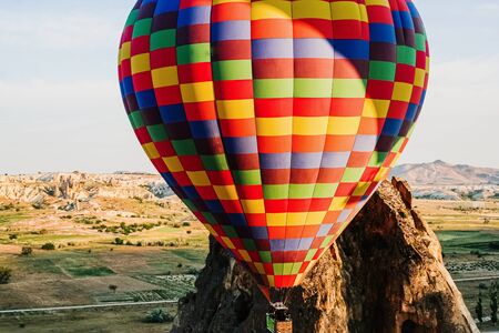 Travelers and tourists flying over mountains at sunset in a colorful aerostat balloon in Goreme, the Turkish cappadocia.の写真素材