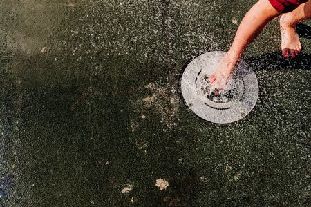 Young barefoot boy running through squirting water in a pool in a spa.の写真素材
