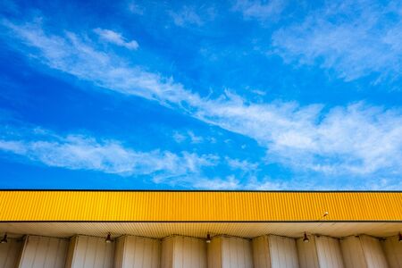 Nice blue sky with clouds, over a yellow canopy of a factory.の写真素材
