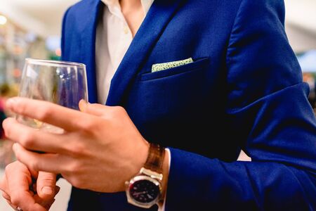 An elegant businessman holds a glass of wine during a business meeting.の写真素材